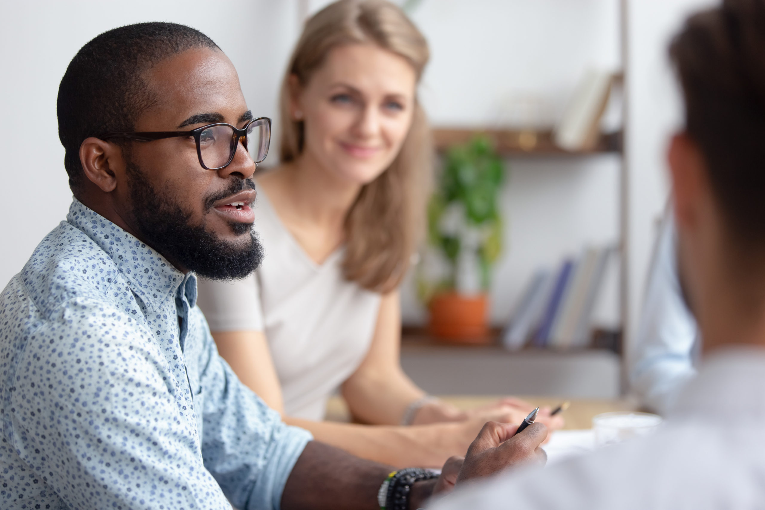 Male african-american talking to coworkers timeout in office Excited male african-american talking to coworkers timeout in office informal partners conversation. Black manager telling interesting story, sharing news, business strategy. Blur background
